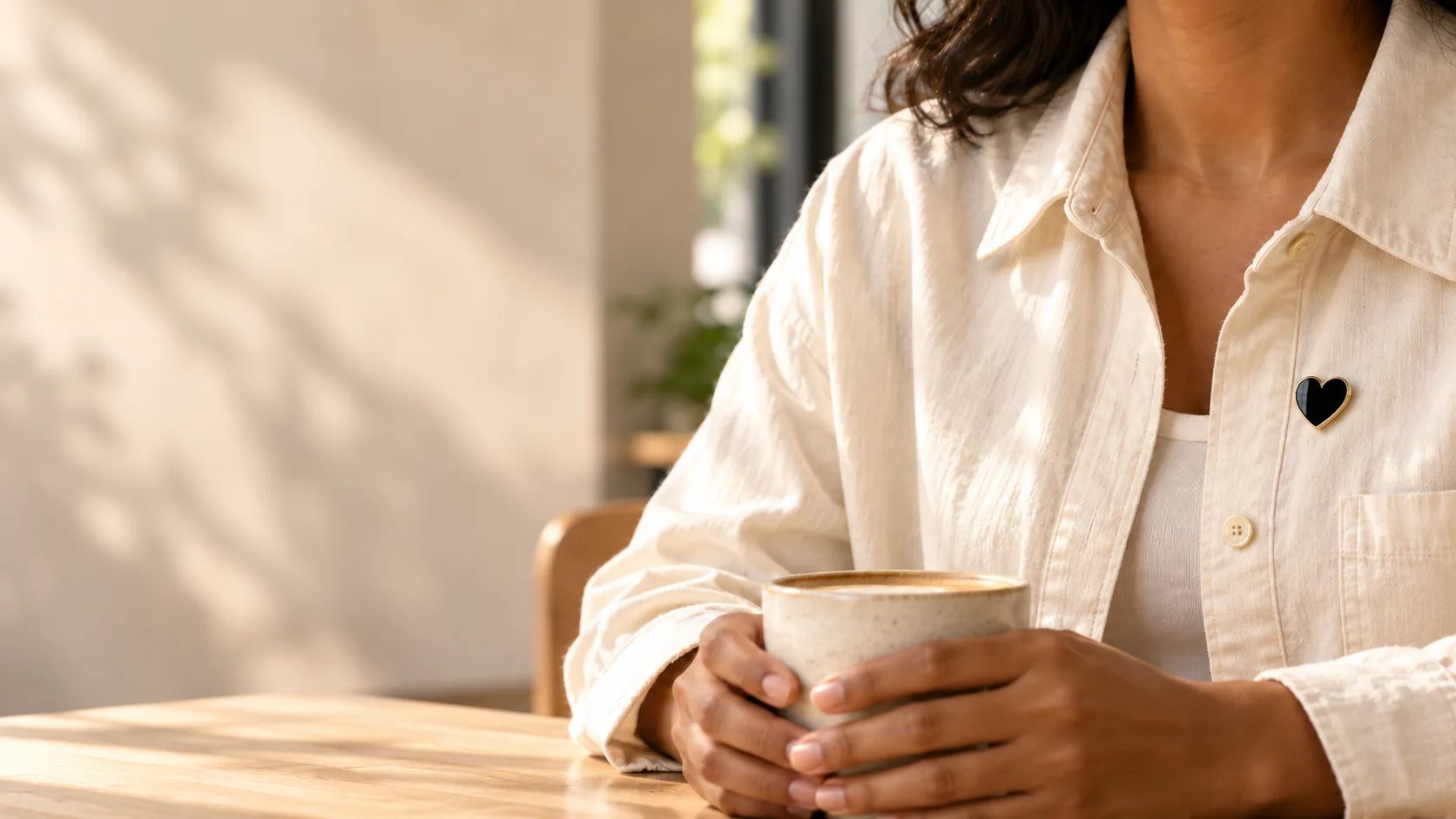 A person wearing The Mourning Heart while holding a warm drink in a café